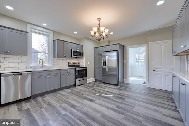 kitchen featuring sink, stainless steel appliances, light hardwood / wood-style flooring, and gray cabinetry