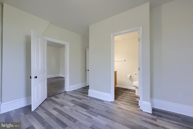 unfurnished bedroom with ensuite bathroom and hardwood / wood-style flooring