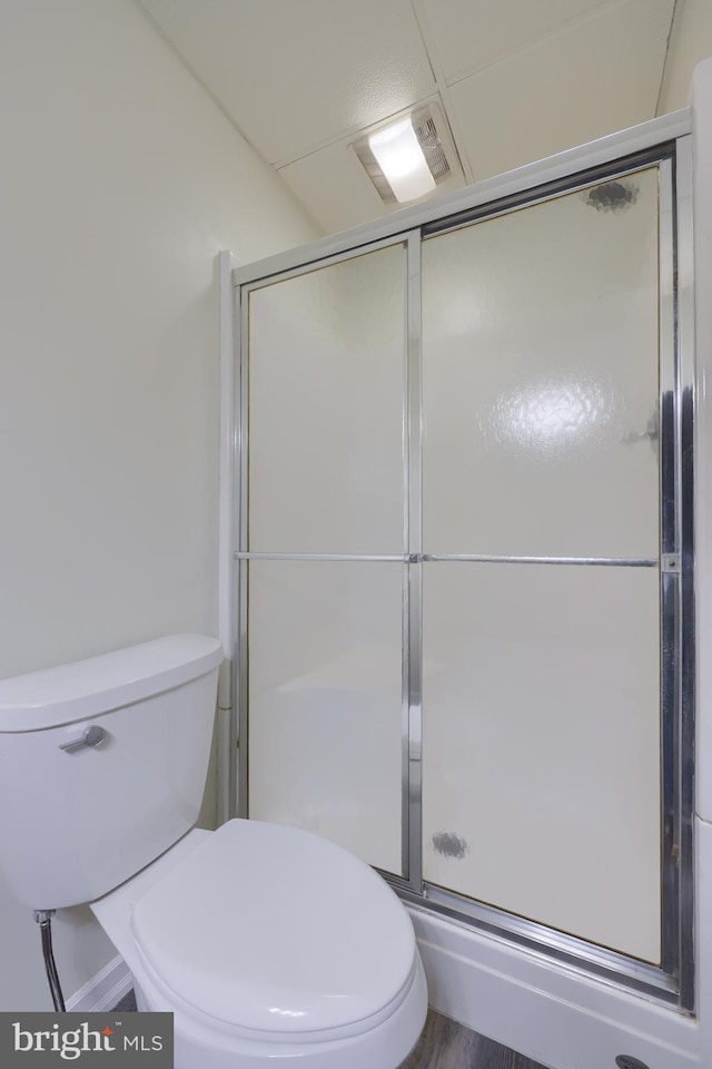 bathroom with toilet, walk in shower, and hardwood / wood-style floors