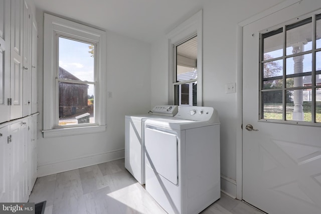 clothes washing area with light hardwood / wood-style floors, washer and dryer, and a healthy amount of sunlight