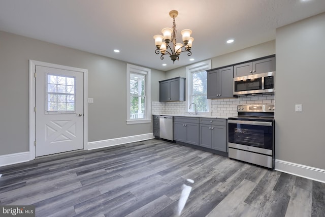 kitchen featuring appliances with stainless steel finishes, decorative backsplash, dark wood-type flooring, and gray cabinetry