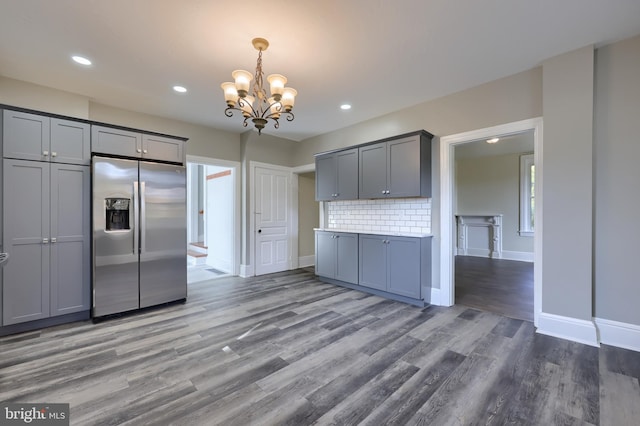 kitchen featuring backsplash, stainless steel fridge with ice dispenser, dark hardwood / wood-style floors, gray cabinetry, and a notable chandelier