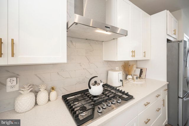 kitchen featuring backsplash, stainless steel appliances, wall chimney exhaust hood, and white cabinets