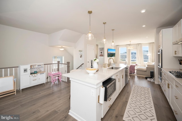 kitchen featuring dark hardwood / wood-style flooring, white cabinetry, a kitchen island with sink, pendant lighting, and stainless steel appliances