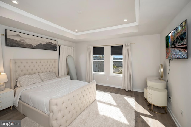 bedroom with a raised ceiling and dark hardwood / wood-style flooring