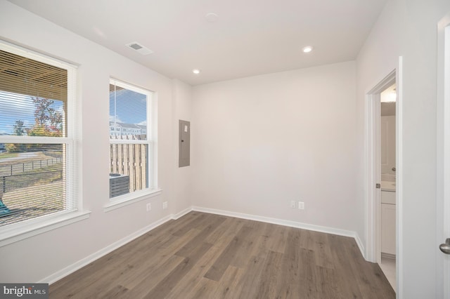 empty room featuring electric panel and dark hardwood / wood-style flooring