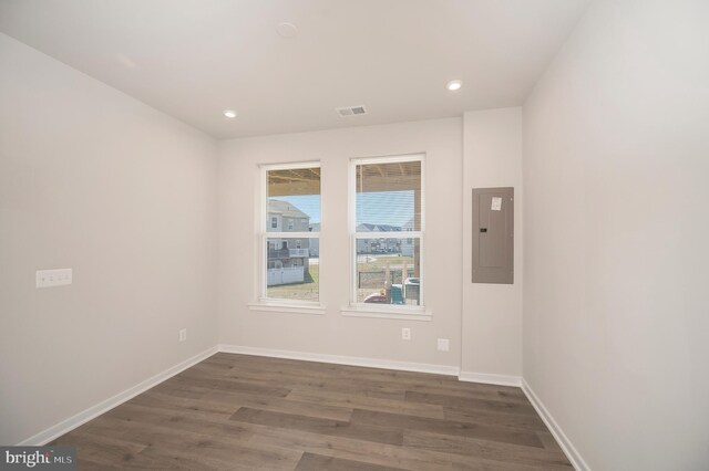 spare room with electric panel and dark hardwood / wood-style flooring