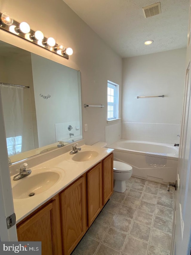 bathroom with toilet, a tub, tile patterned flooring, vanity, and a textured ceiling