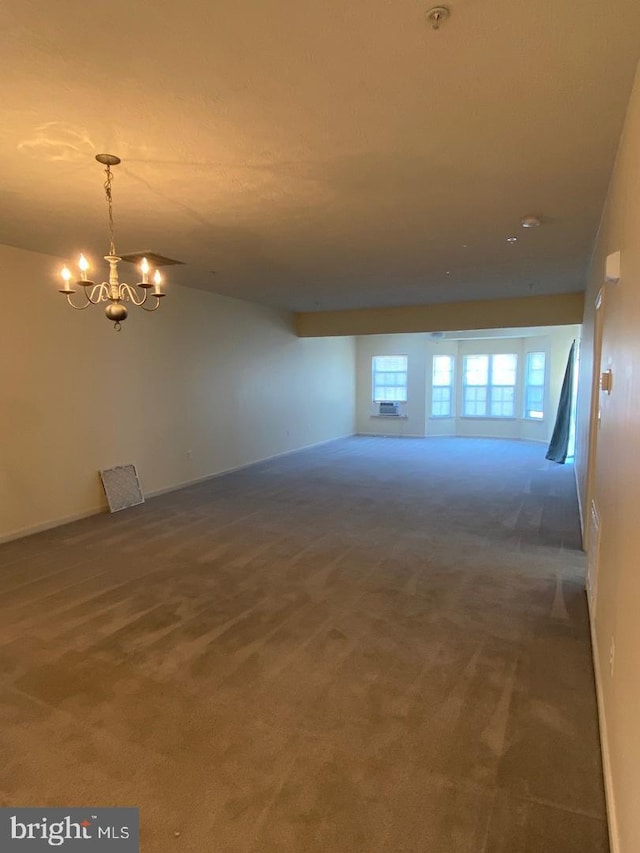 carpeted empty room with a notable chandelier