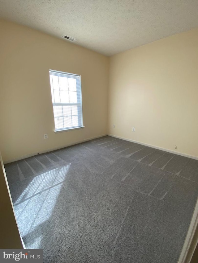 carpeted spare room with a textured ceiling