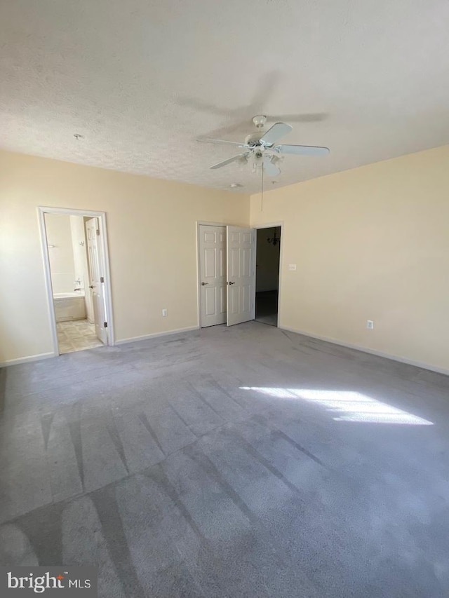 unfurnished bedroom with light carpet, a textured ceiling, ensuite bathroom, and ceiling fan