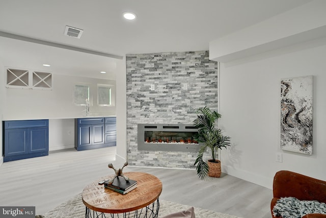 living room featuring indoor wet bar, light hardwood / wood-style flooring, and a fireplace