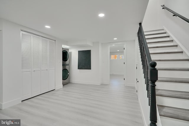 laundry room featuring stacked washer / dryer and light wood-type flooring