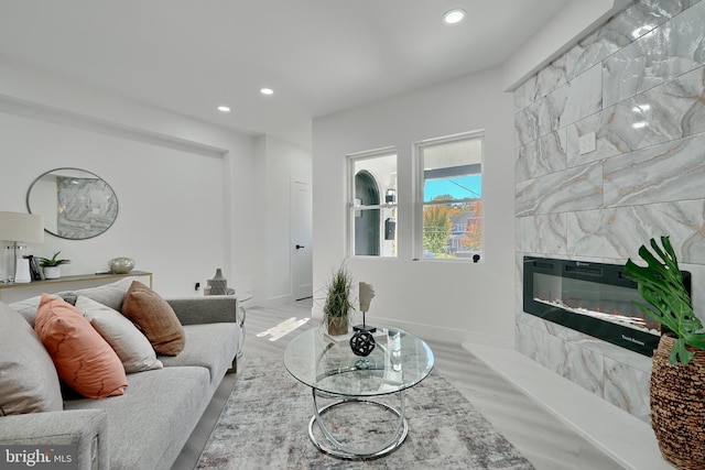 living room featuring a tiled fireplace and light wood-type flooring