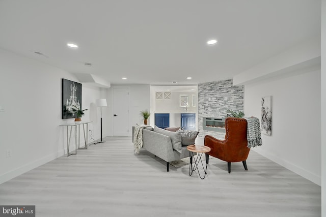 living room with a stone fireplace and light hardwood / wood-style flooring