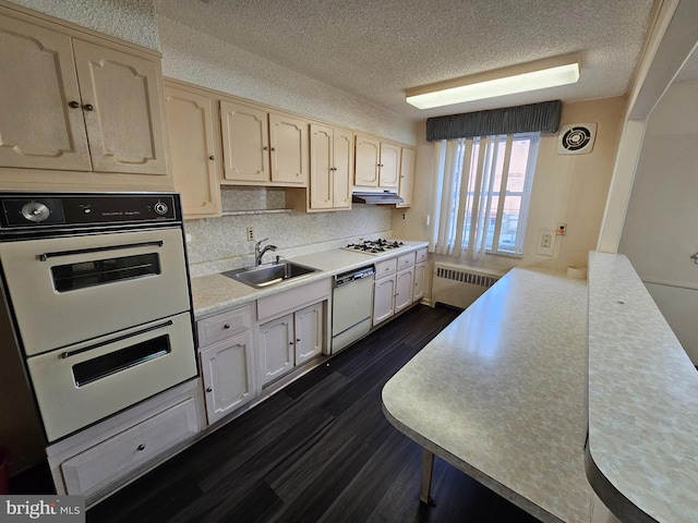 kitchen featuring dark hardwood / wood-style flooring, a textured ceiling, radiator, sink, and white appliances