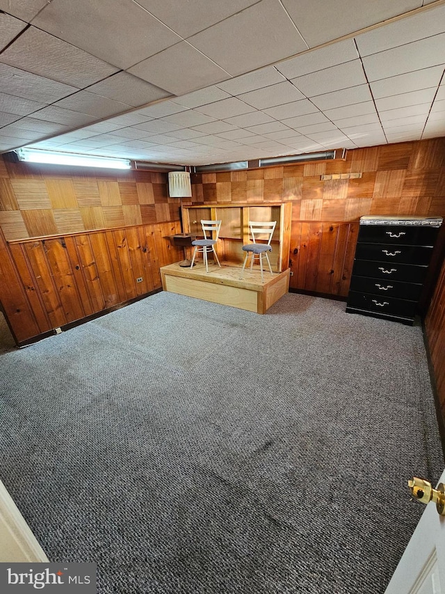 basement featuring carpet flooring and wooden walls