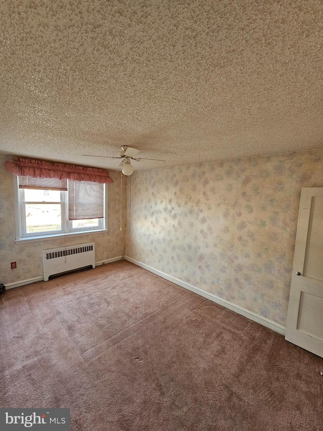 empty room featuring a textured ceiling, ceiling fan, radiator heating unit, and carpet flooring