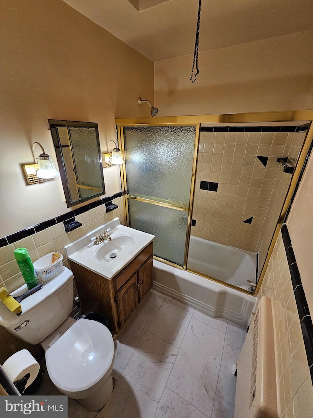 full bathroom with tile walls, vanity, bath / shower combo with glass door, and toilet