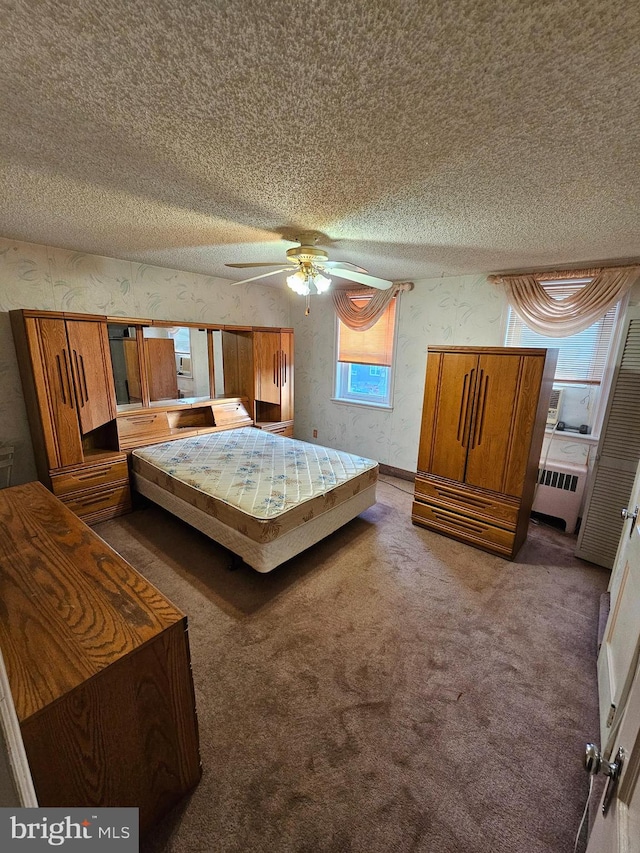 unfurnished bedroom featuring ceiling fan, a textured ceiling, multiple windows, and dark carpet