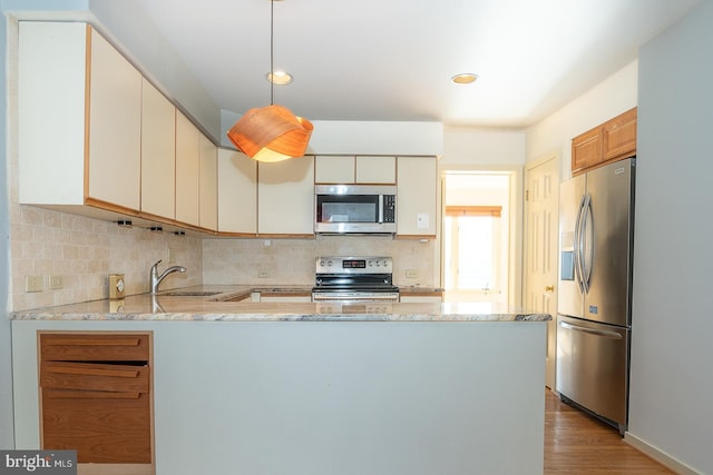 kitchen with decorative light fixtures, sink, backsplash, kitchen peninsula, and stainless steel appliances