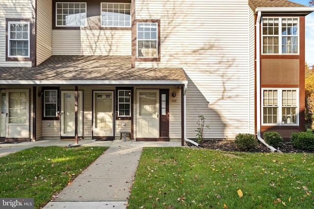 view of exterior entry with covered porch and a lawn