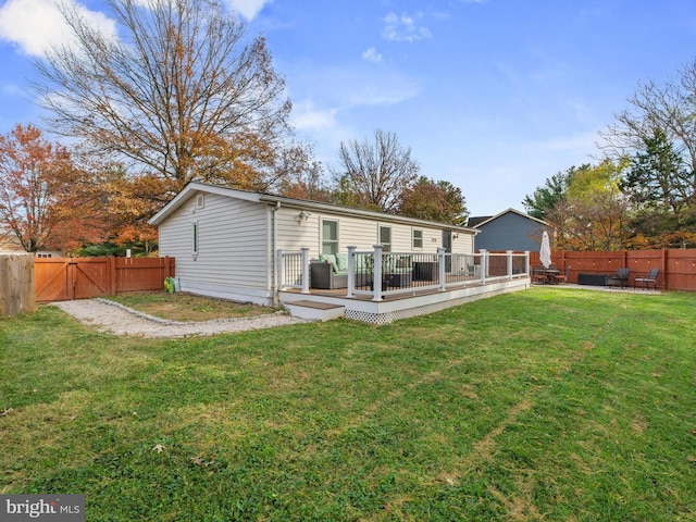 rear view of house with a wooden deck and a yard