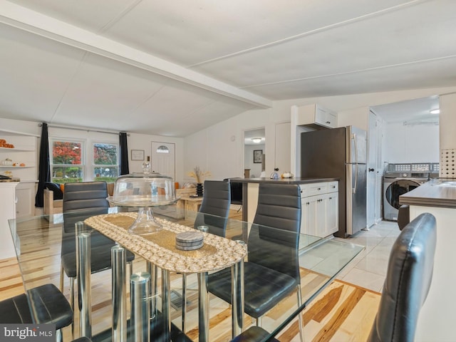 dining space with light wood-type flooring, vaulted ceiling with beams, and washer / dryer