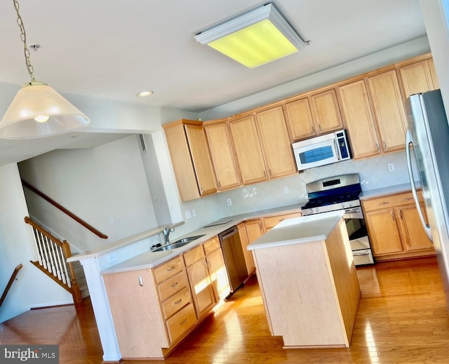 kitchen with pendant lighting, a center island, light wood-type flooring, and appliances with stainless steel finishes