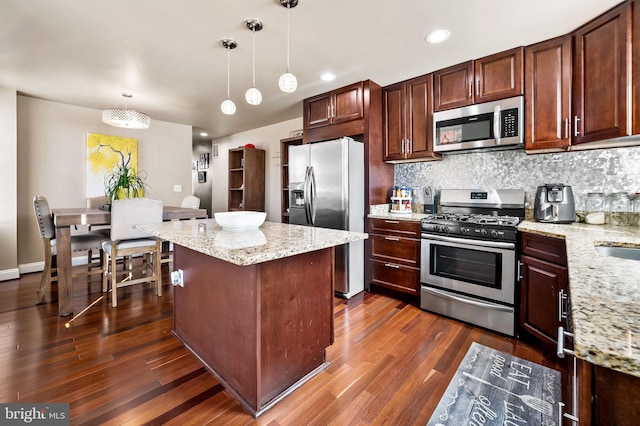 kitchen with stainless steel appliances, light stone countertops, pendant lighting, dark hardwood / wood-style flooring, and tasteful backsplash