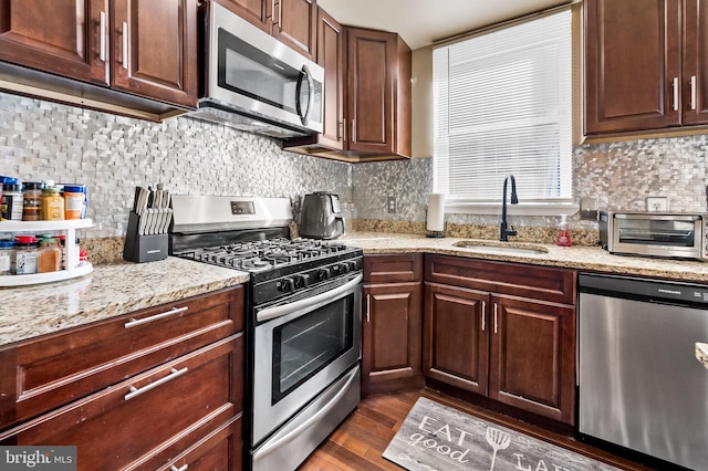 kitchen featuring decorative backsplash, light stone counters, dark hardwood / wood-style floors, sink, and stainless steel appliances