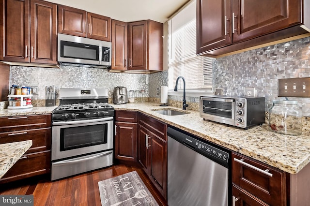 kitchen featuring backsplash, dark hardwood / wood-style flooring, stainless steel appliances, sink, and light stone counters