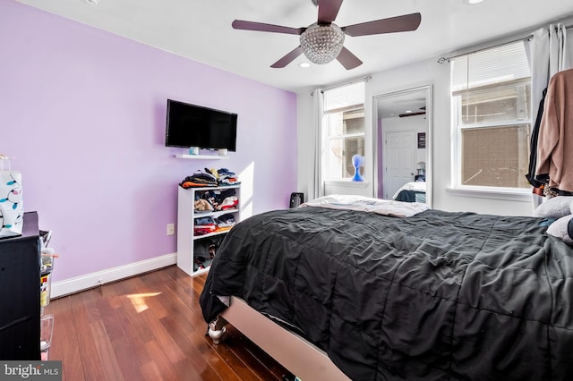 bedroom with ceiling fan, multiple windows, and dark hardwood / wood-style flooring