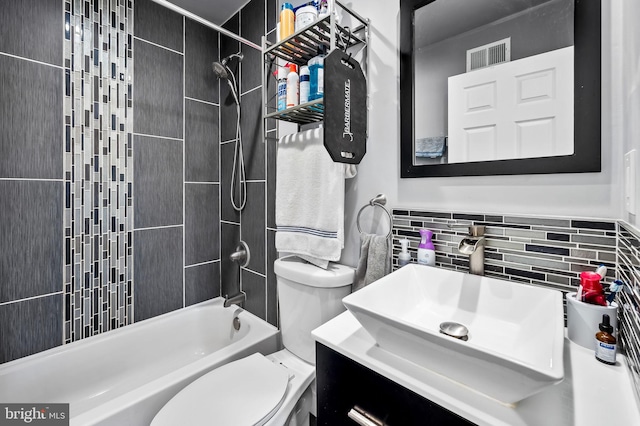 full bathroom with vanity, tiled shower / bath, toilet, and tile walls