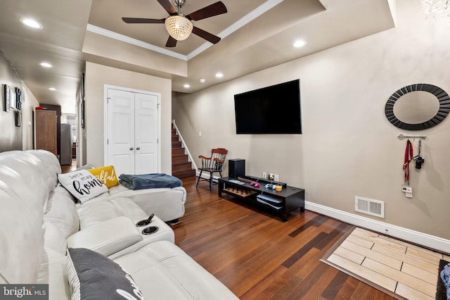 living room featuring ceiling fan, crown molding, dark hardwood / wood-style flooring, and a raised ceiling