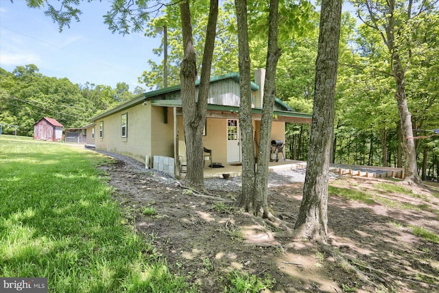 view of side of property featuring a storage shed, a patio area, and a lawn