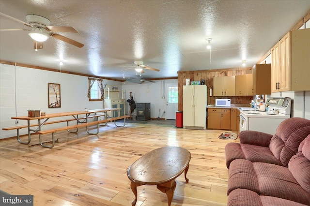 living room featuring light hardwood / wood-style flooring, a wood stove, and a textured ceiling