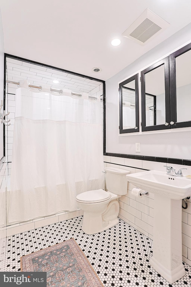 bathroom featuring tile patterned floors, a shower with curtain, tile walls, and toilet