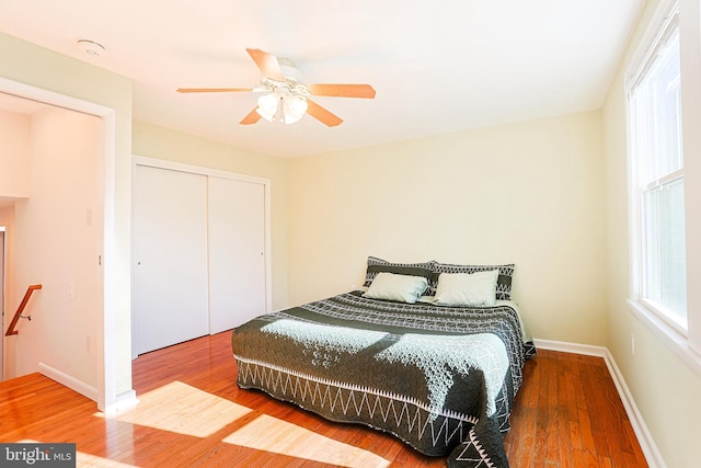 bedroom with a closet, hardwood / wood-style flooring, and ceiling fan