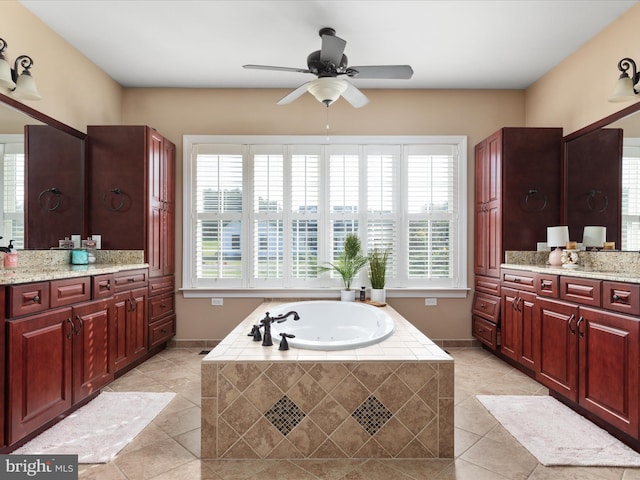 bathroom featuring vanity, a relaxing tiled tub, and a healthy amount of sunlight