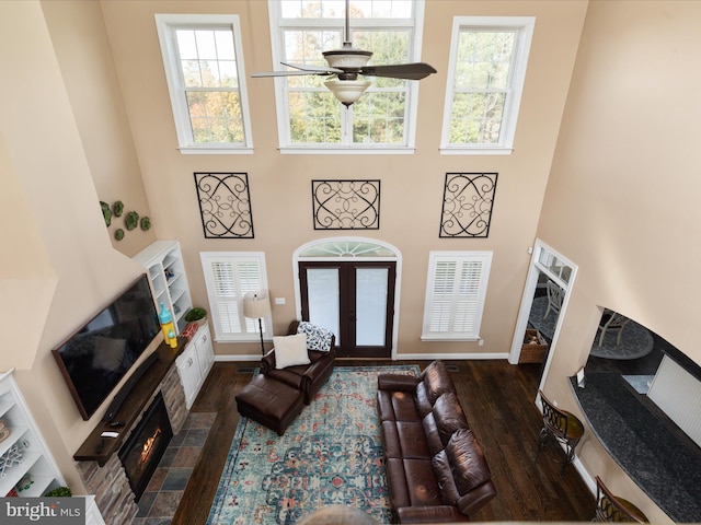 living room with ceiling fan, dark hardwood / wood-style flooring, plenty of natural light, and a high ceiling