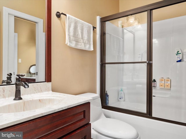 full bathroom featuring vanity, combined bath / shower with glass door, and toilet