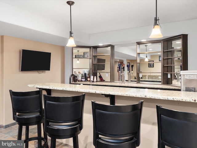 kitchen featuring pendant lighting, light stone counters, and a kitchen bar