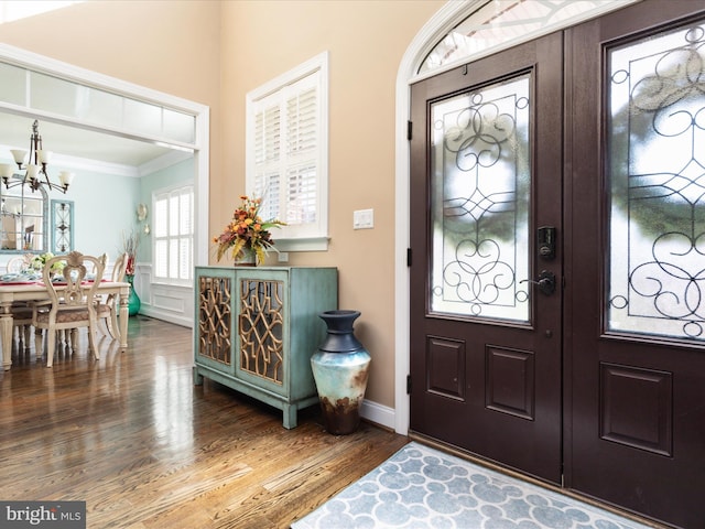 foyer with an inviting chandelier, crown molding, and hardwood / wood-style floors