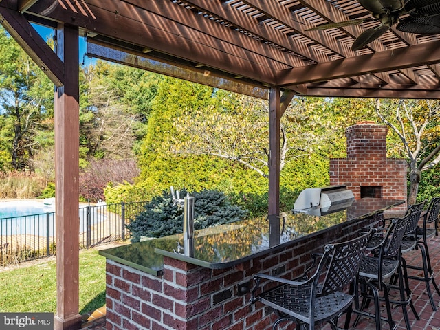 view of patio with a bar, a grill, an outdoor kitchen, a pergola, and ceiling fan