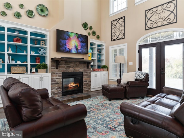 living room with hardwood / wood-style flooring, a towering ceiling, plenty of natural light, and a fireplace