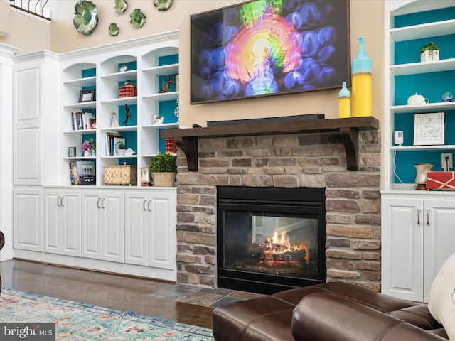 living room featuring dark wood-type flooring, a fireplace, and built in shelves