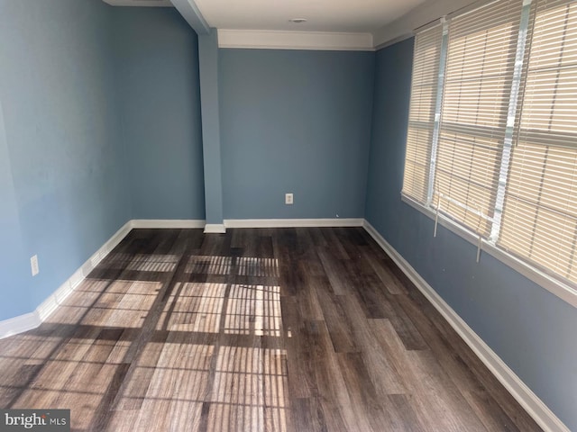 empty room with dark hardwood / wood-style flooring, ornamental molding, and a wealth of natural light