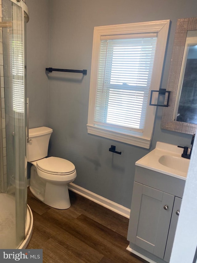 bathroom with hardwood / wood-style floors, vanity, toilet, and a shower with shower door