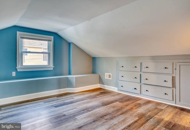 bonus room with light wood-type flooring and vaulted ceiling